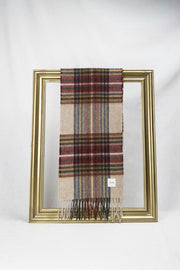 A beautifully designed beige tartan wool scarf featuring red, blue, and yellow checkered patterns is elegantly draped over a gold frame against a white background. The soft texture and timeless plaid design make it a perfect winter accessory and a thoughtful gift for her. Available with fast delivery across Malta.