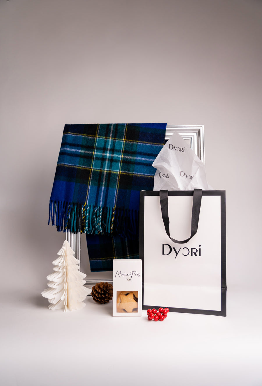 A soft blue and green tartan wool scarf from Dyori, paired with festive decorations and mince pies for a cozy Christmas vibe.