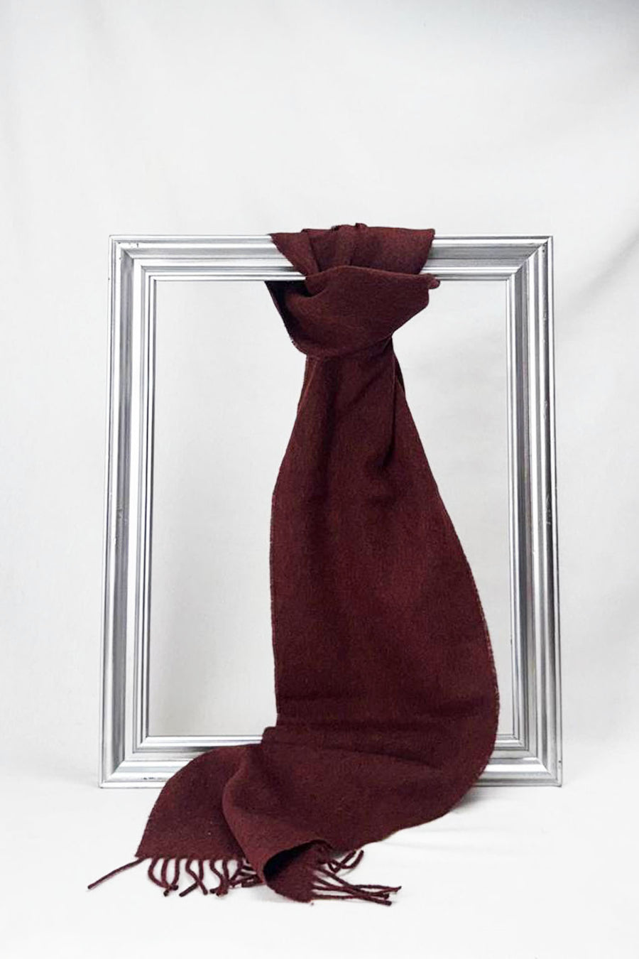 Rich burgundy merino wool scarf elegantly draped over a silver frame. Soft, warm, and beautifully woven — a timeless unisex winter accessory and thoughtful gift. Delivered in Malta.
