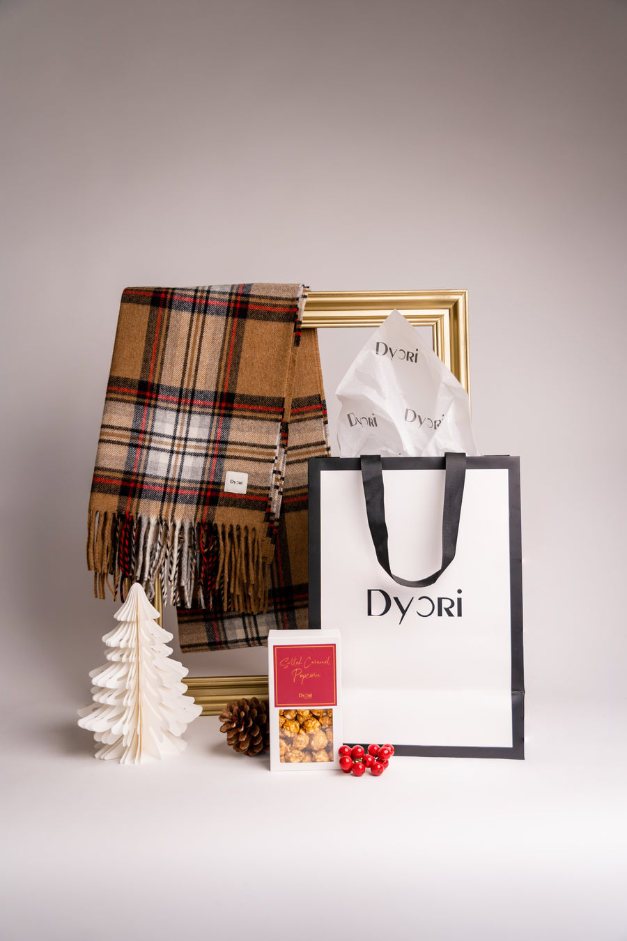 A warm-toned brown and beige cotton scarf with festive accents, styled elegantly with Dyori’s Christmas-themed packaging and treats.
