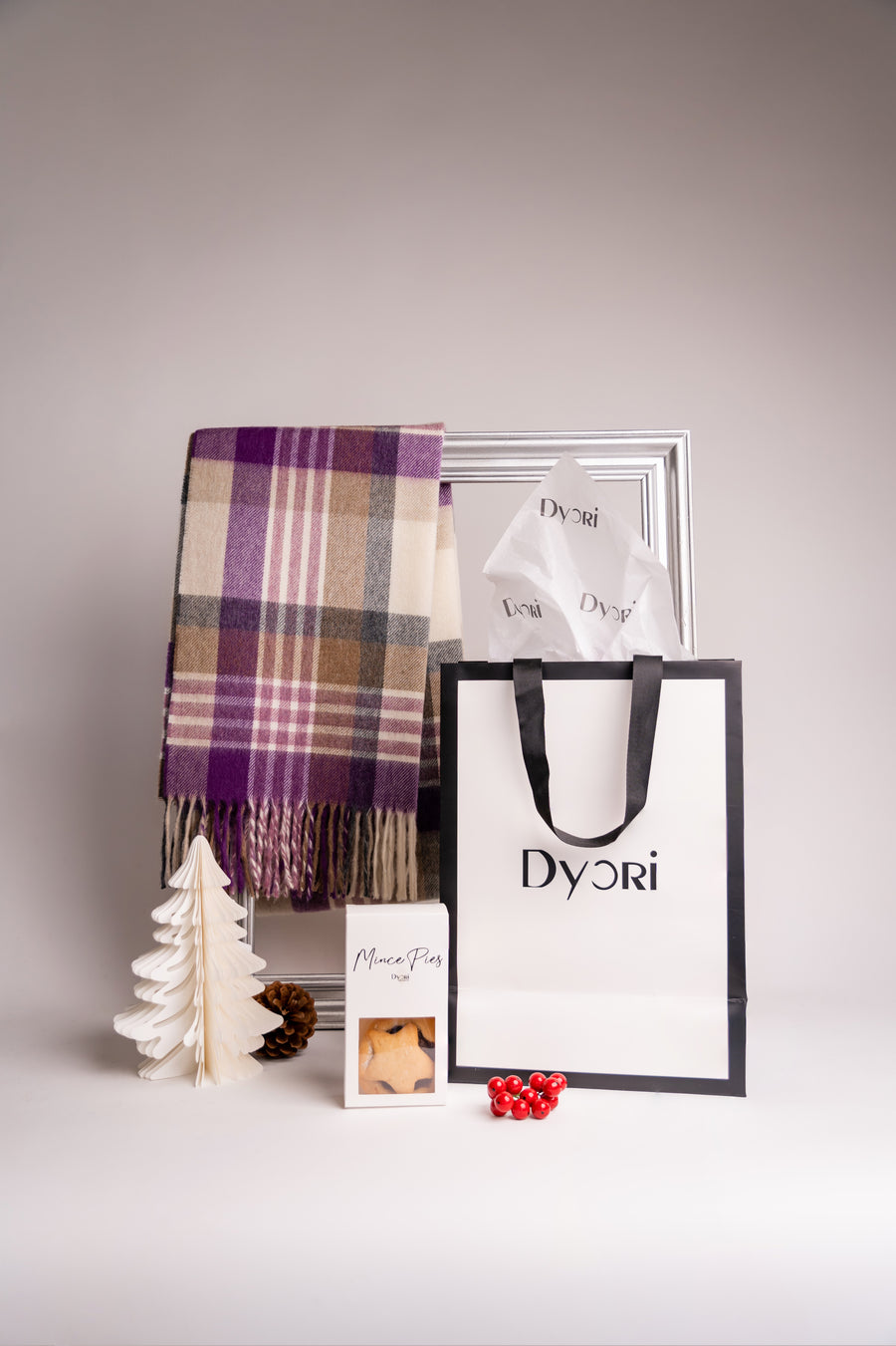 A chic purple and beige merino wool scarf by Dyori, set against a silver frame and Christmas-inspired decor — blending timeless charm with seasonal warmth.