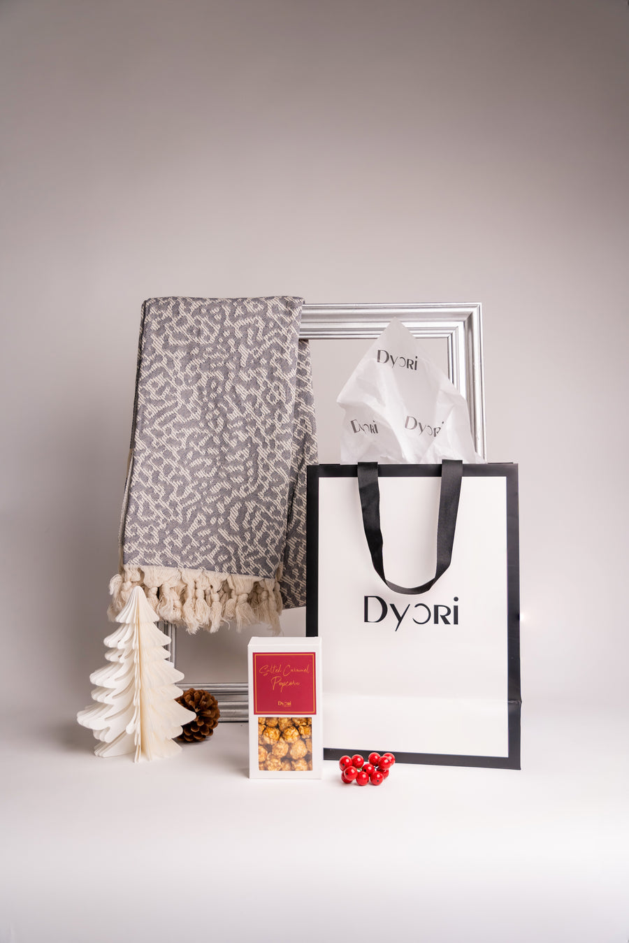 A luxurious ash grey 100% cotton shawl made in Turkey, featuring a soft jacquard weave with tasseled edges, displayed with a Dyori gift bag and festive treats.