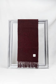 Luxurious solid burgundy merino wool scarf neatly folded to display its fine texture and fringe details. A cozy and stylish gift for him or her, available in Malta.