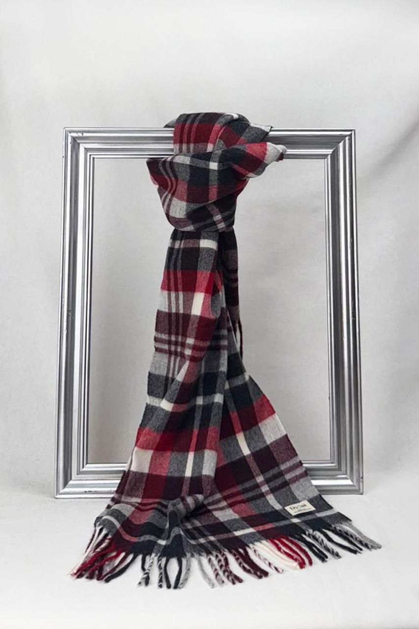 A beautifully folded red, black, and white tartan scarf neatly hung on a silver frame, showcasing its cozy wool texture and fringe ends. A timeless accessory and elegant Christmas present for loved ones during the winter season.