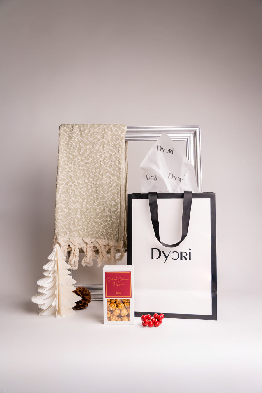 Soft green tea–coloured 100% cotton shawl with an elegant jacquard pattern and tasseled edges, artfully displayed with Dyori gift packaging and festive accents.