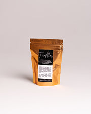 Brown packaging of truffles with a label on a light gray background. Gourmet Gifts Malta