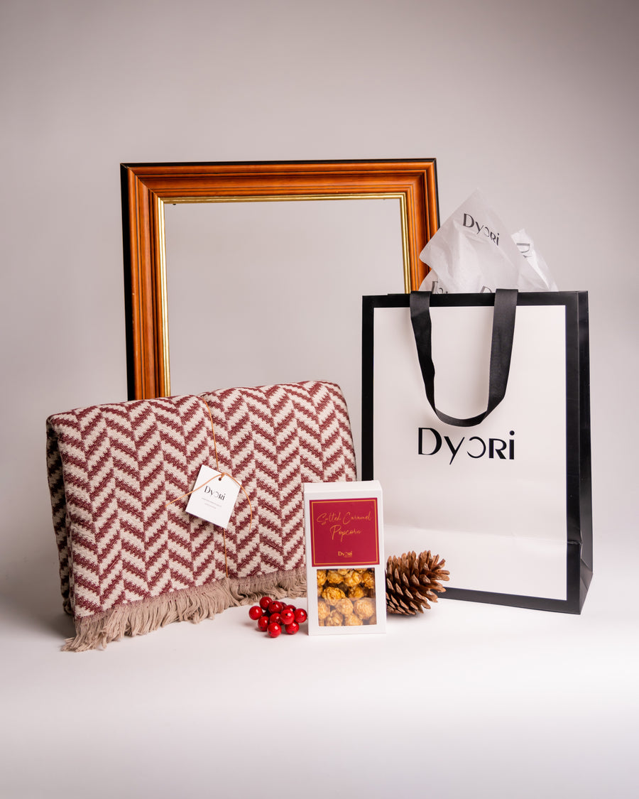 A luxurious cotton throw in a red and cream chevron pattern, beautifully gift-packed with gourmet salted caramel popcorn and presented in an elegant Dyori bag – the perfect sustainable Christmas gift in Malta for men, women, teachers, or corporate clients.