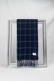 Luxurious merino wool scarf in midnight navy with elegant windowpane checks, beautifully draped on a silver frame. Soft, warm, and timeless — a perfect winter gift for him or for her. Delivered in Malta.