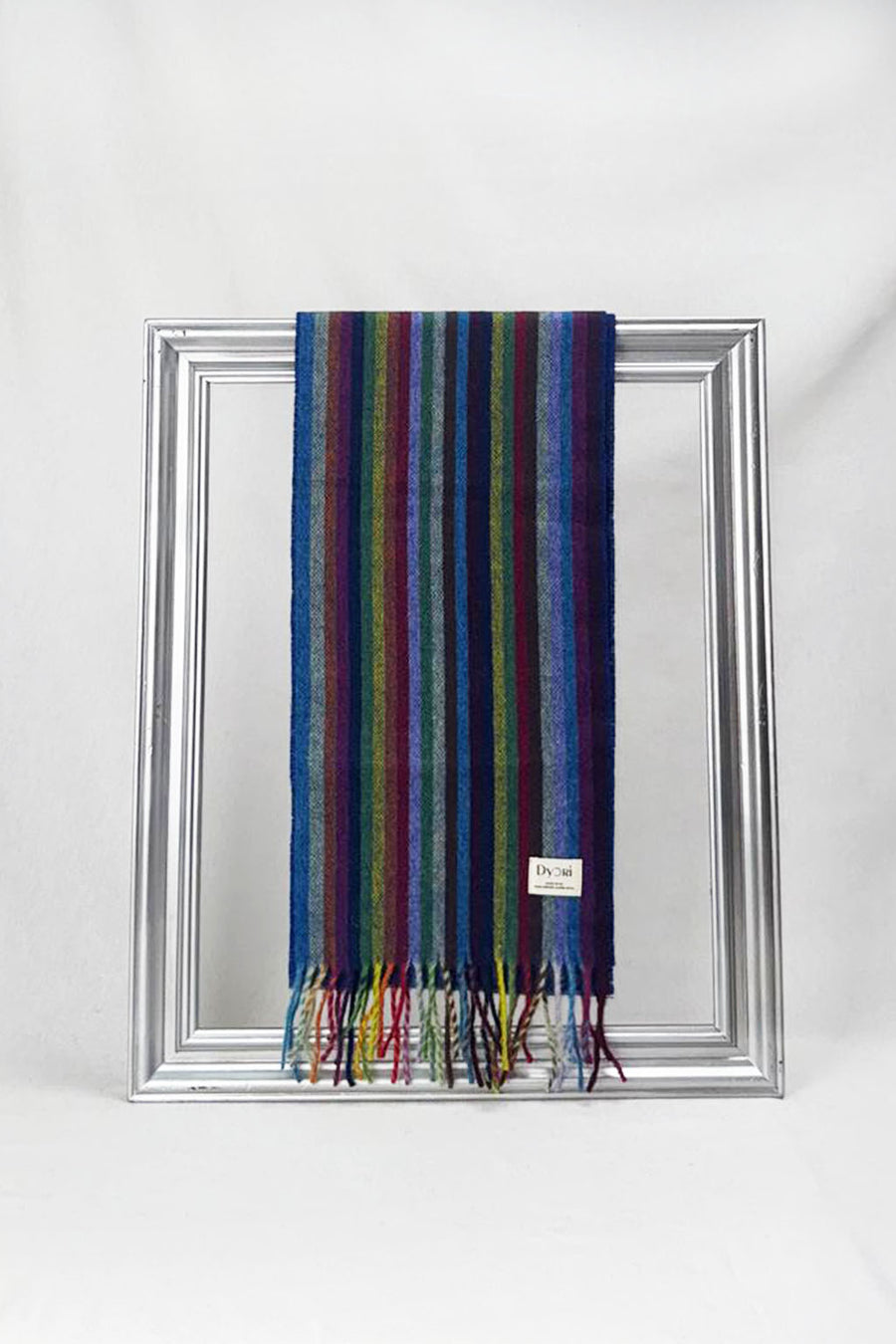 Bright multicolour merino wool scarf with elegant vertical stripes, draped gracefully over a silver frame. A soft, stylish unisex accessory — perfect as a winter gift in Malta.