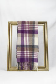 A luxurious plaid wool scarf featuring shades of purple, beige, grey, and cream is elegantly draped through a gold picture frame against a white background. This stylish winter accessory highlights warmth and sophistication, making it an ideal gift for her. Available with fast delivery across Malta.