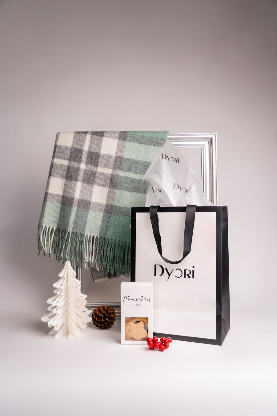 Soft wool shawl in sage green, grey, and cream check pattern with fringe edges, displayed with Dyorí gift packaging and mince pies.