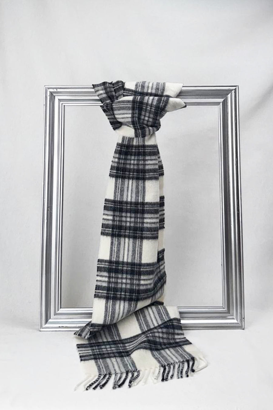 Luxurious grey and white plaid merino wool scarf with delicate fringes. A soft, warm, and stylish piece designed for comfort and timeless fashion appeal.