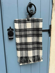 Elegant merino wool scarf in a white and grey check pattern, softly draped over a silver frame. A cozy and sophisticated unisex accessory, perfect for winter in Malta.
