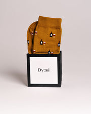 Mustard yellow socks with wine-themed design in a black box with 'Dyori' branding on a light gray background. Secret santa gifts 