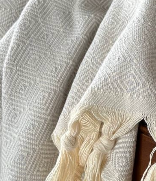 A luxurious Turkish cotton blanket in a Light grey diamond weave pattern, beautifully folded beside a Dyori signature gift bag and a box of salted caramel popcorn. The perfect blend of comfort and elegance for cosy evenings or thoughtful gifting