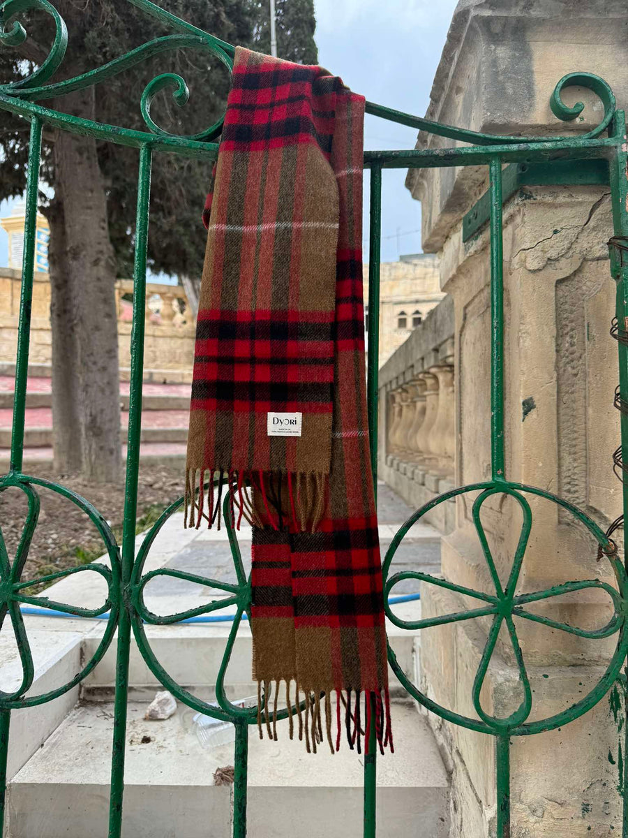 Elegant merino wool scarf in a rich brown and red check pattern with fringed edges, draped over a silver frame. A timeless unisex winter accessory, available in Malta.