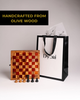 Handmade 22cm olive wood chess board displayed with wooden chess pieces and a Dyori gift bag in the background.
