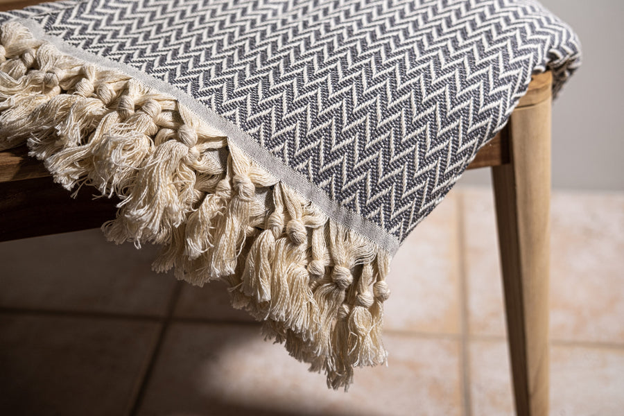Maia-Dyori Charcoal Herringbone Turkish Cotton Throw – 100% cotton blanket featuring a dark grey and cream chevron weave with hand-knotted tassels, artisan made in Turkey