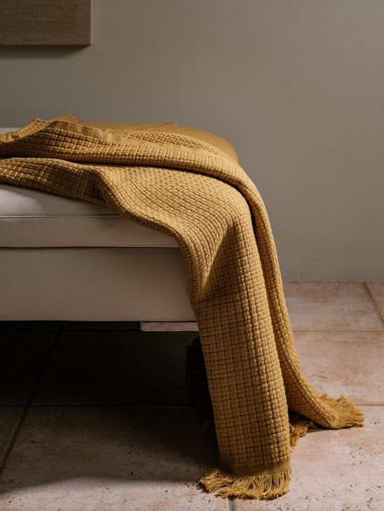 A luxurious Turkish cotton throw in a warm honey mustard, featuring a soft waffle texture and fringed edges — perfect for adding a pop of colour and cozy comfort to any space